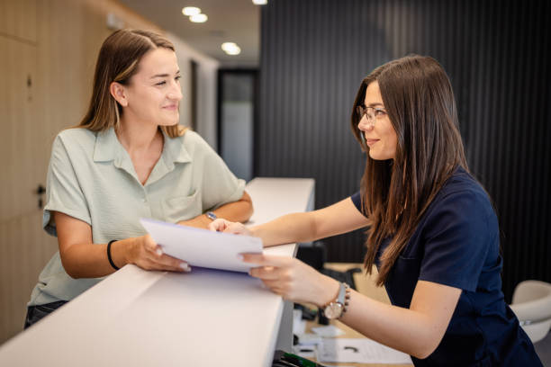 Dental clinic front desk staff assisting patient with paperwork and appointment details